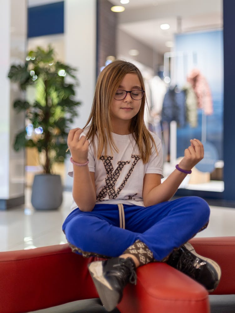 Young Model In Louis Vuitton Clothes Meditating Sitting Cross-legged In A Shopping Mall