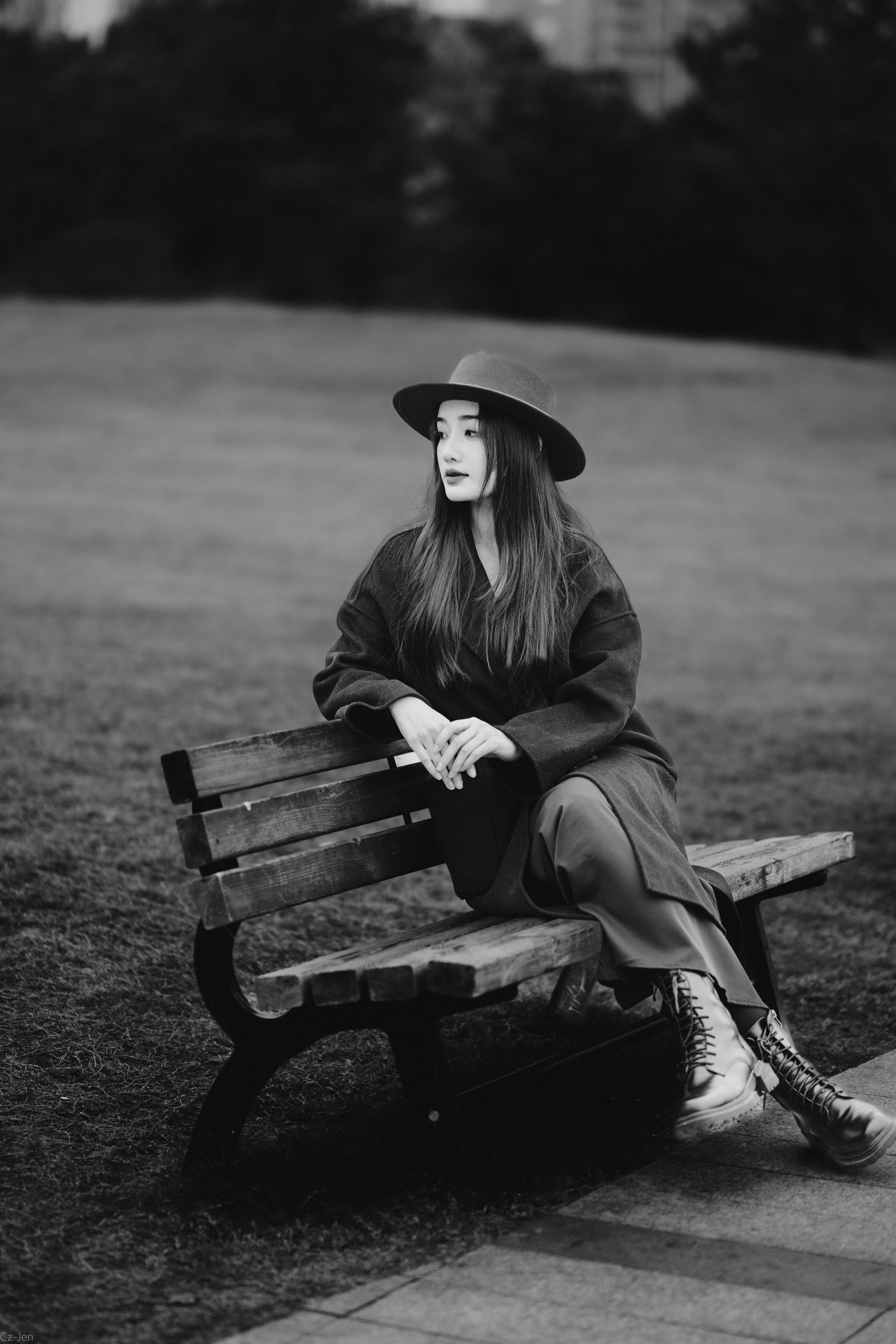 Portrait of a stylish woman in a hat sitting pensively on a park bench in Changsha.