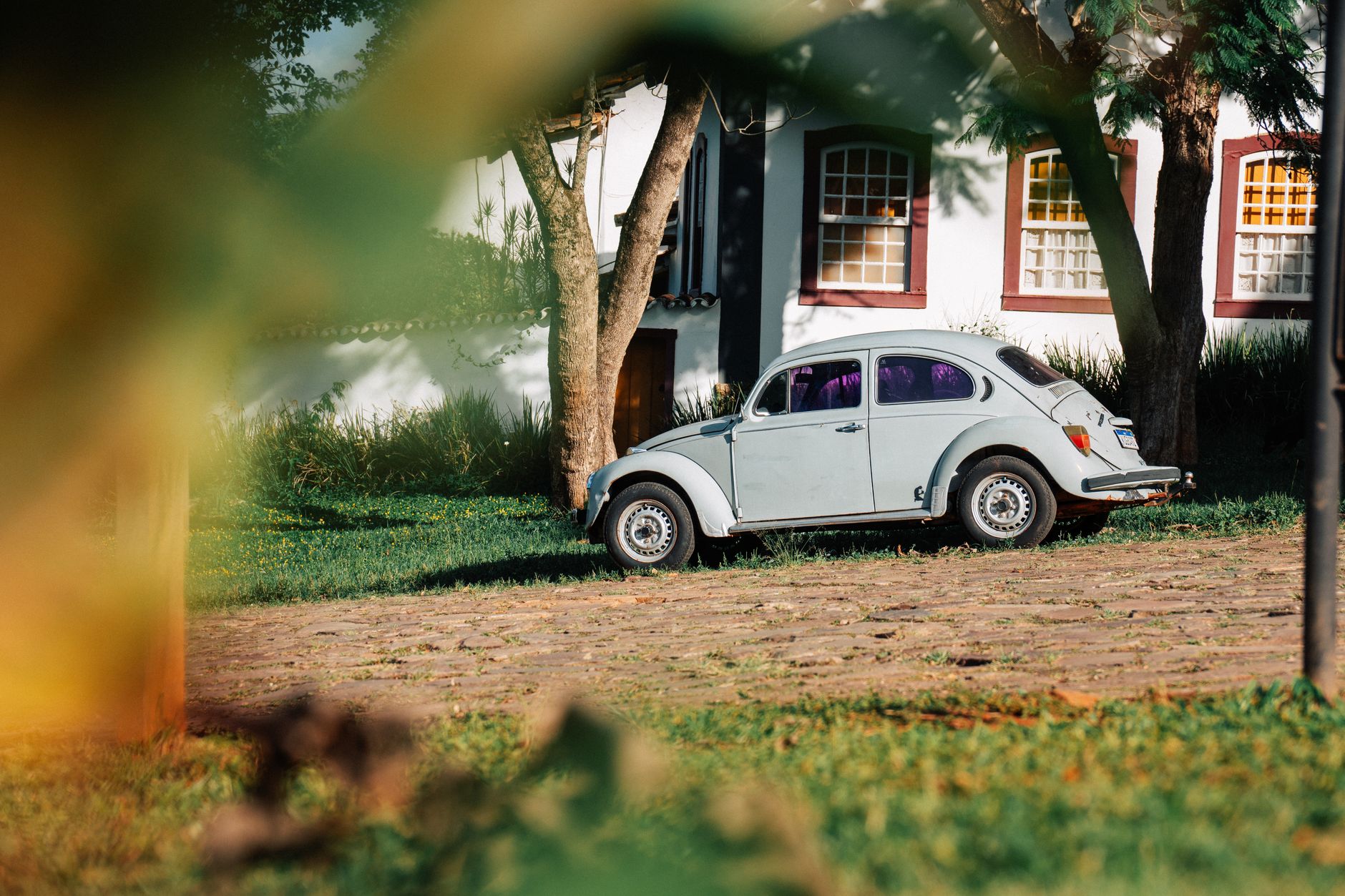 A vintage Volkswagen Beetle parked outside a charming house surrounded by greenery.