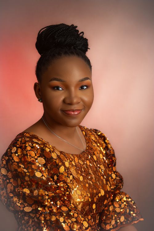 Free Elegant portrait of smiling woman in a golden sequin dress against a soft studio backdrop. Stock Photo