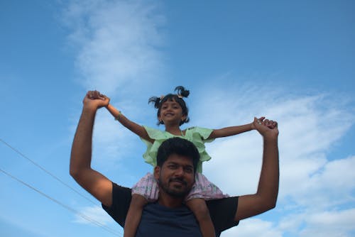 An indian man taking a little child on his shoulder