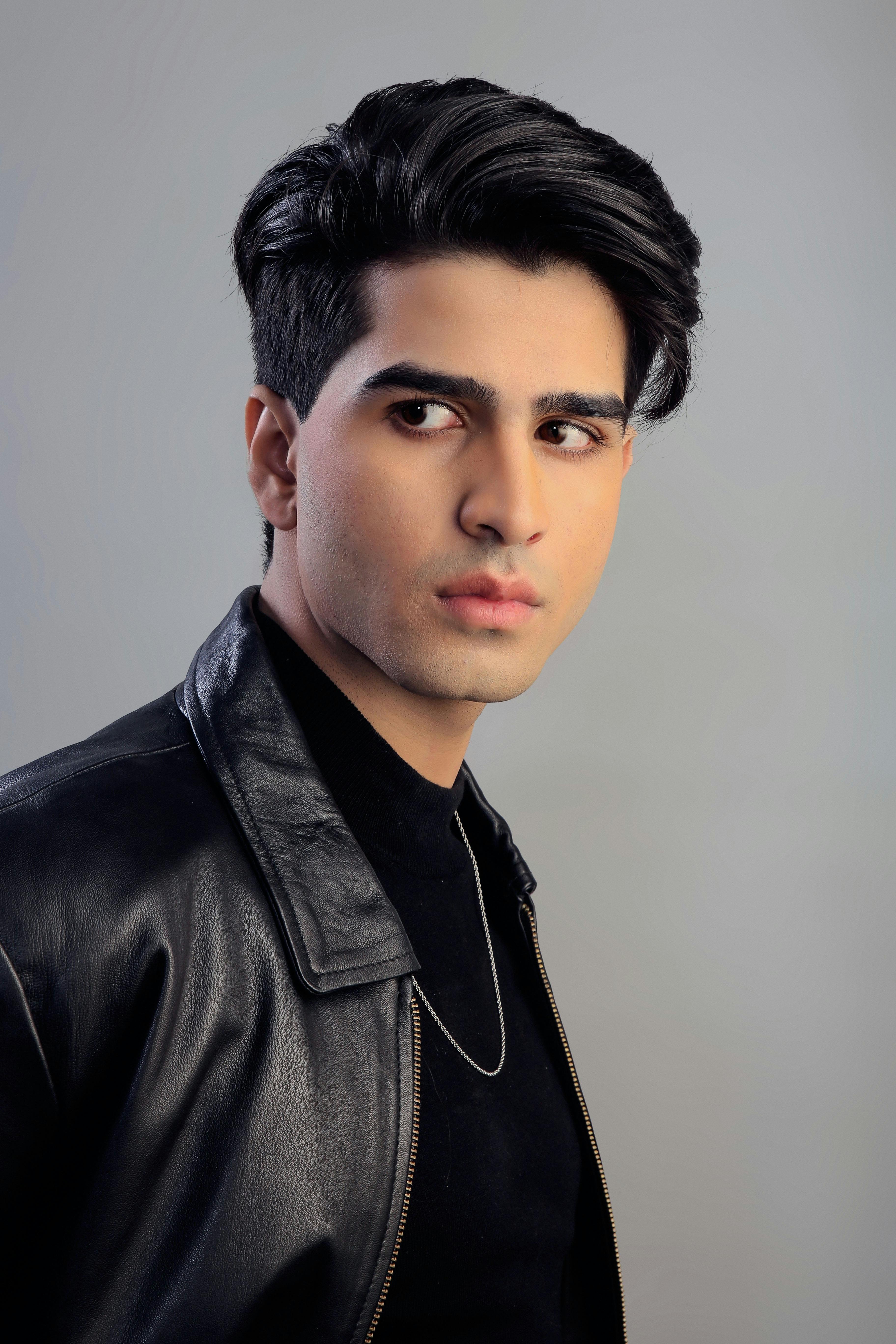 Elegant young man in a leather jacket against a gray background.