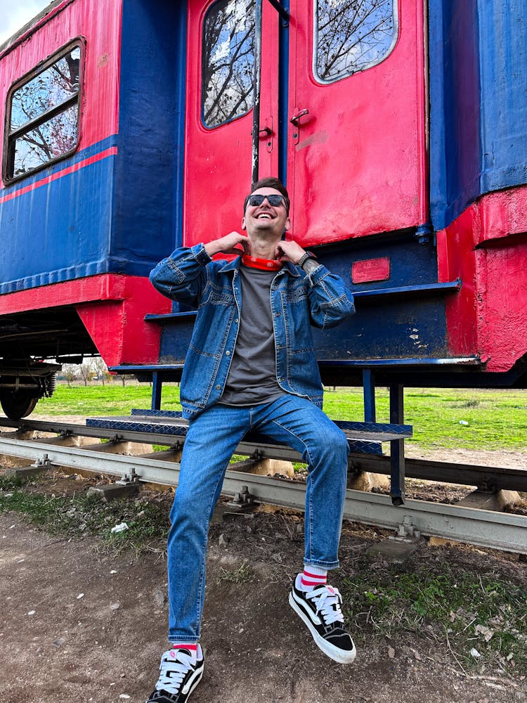 Man Wearing Denim Outfit In Front Of Colorful Carriage 