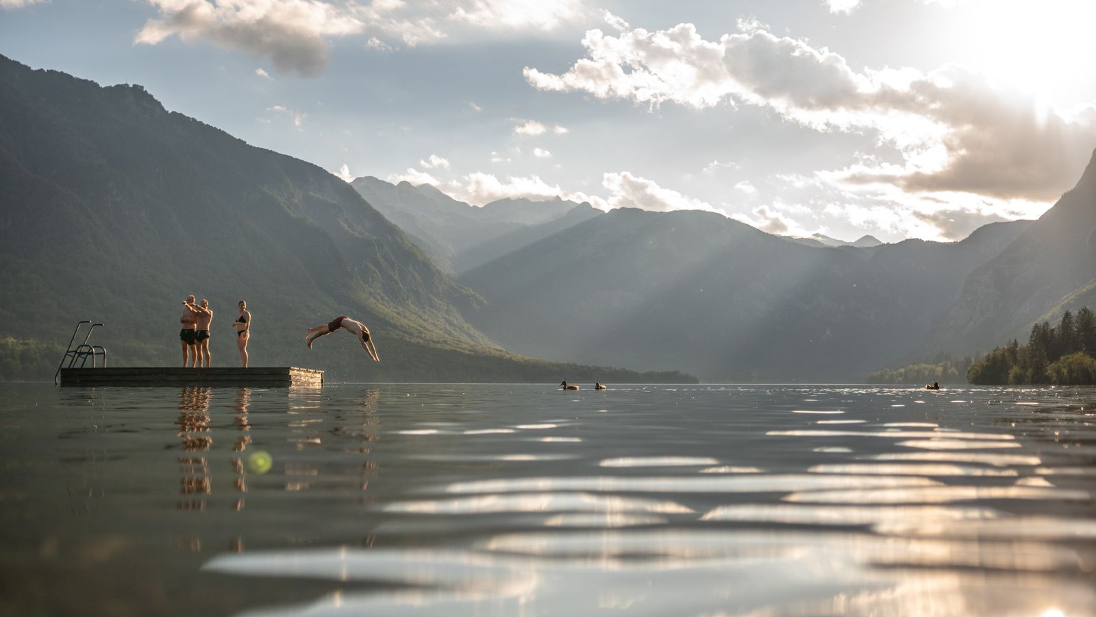 A swimmer launching off a floating platform into a mountain lake — photo by Elias Tigiser on Pexels