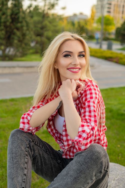 Free Smiling woman in park wearing red checkered shirt enjoying a summer day. Stock Photo