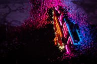 在黑暗雨夜的城市街道上，水坑里映照着五颜六色的霓虹灯标志，以充满活力的现代风格呈现