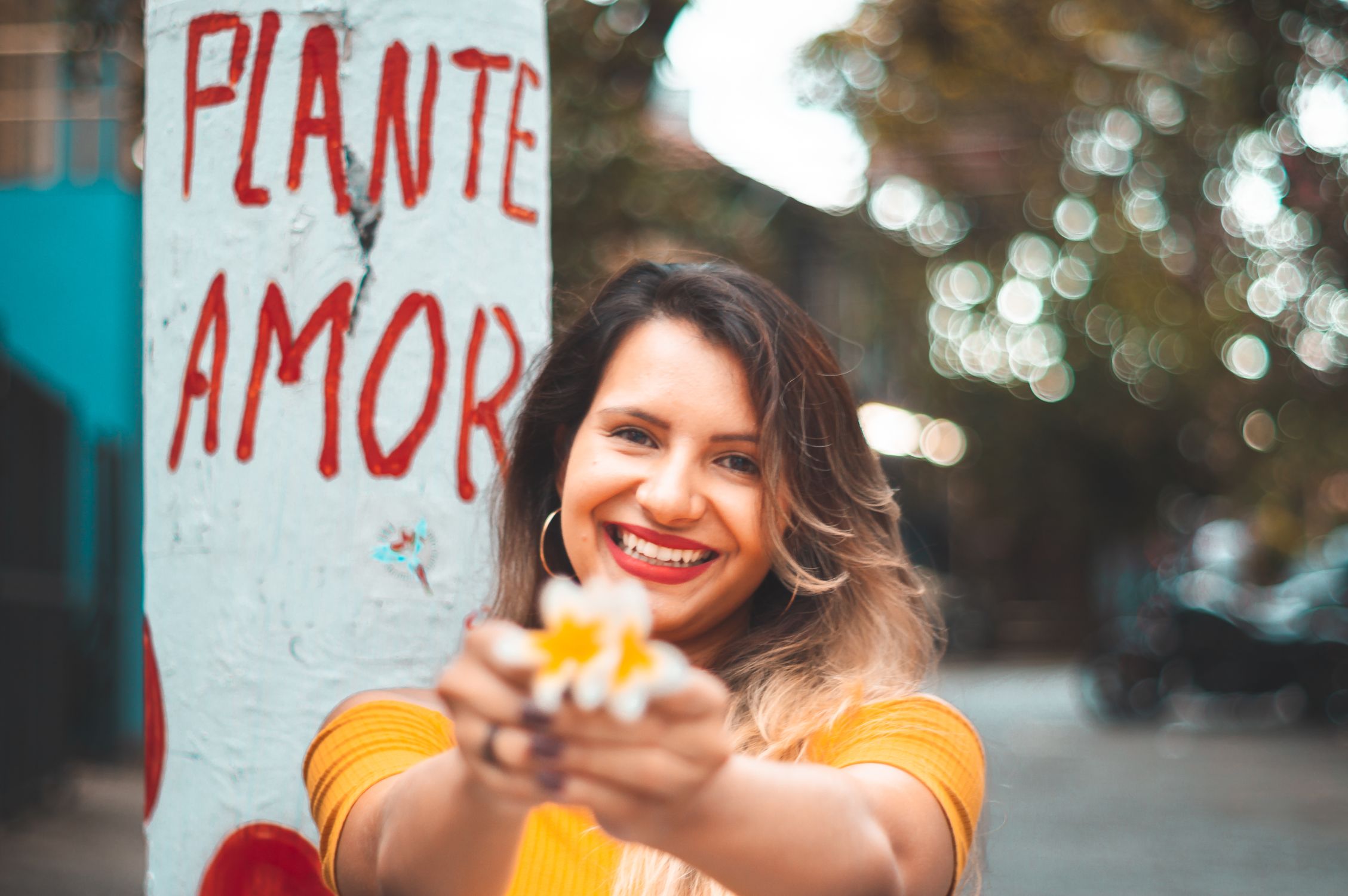 Mulher sorridente segurando uma flor, simbolizando o resgate da autoestima e renovação após o término