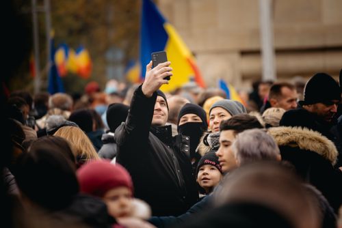 Free A lively outdoor gathering with a diverse crowd taking selfies amid colorful flags. Stock Photo