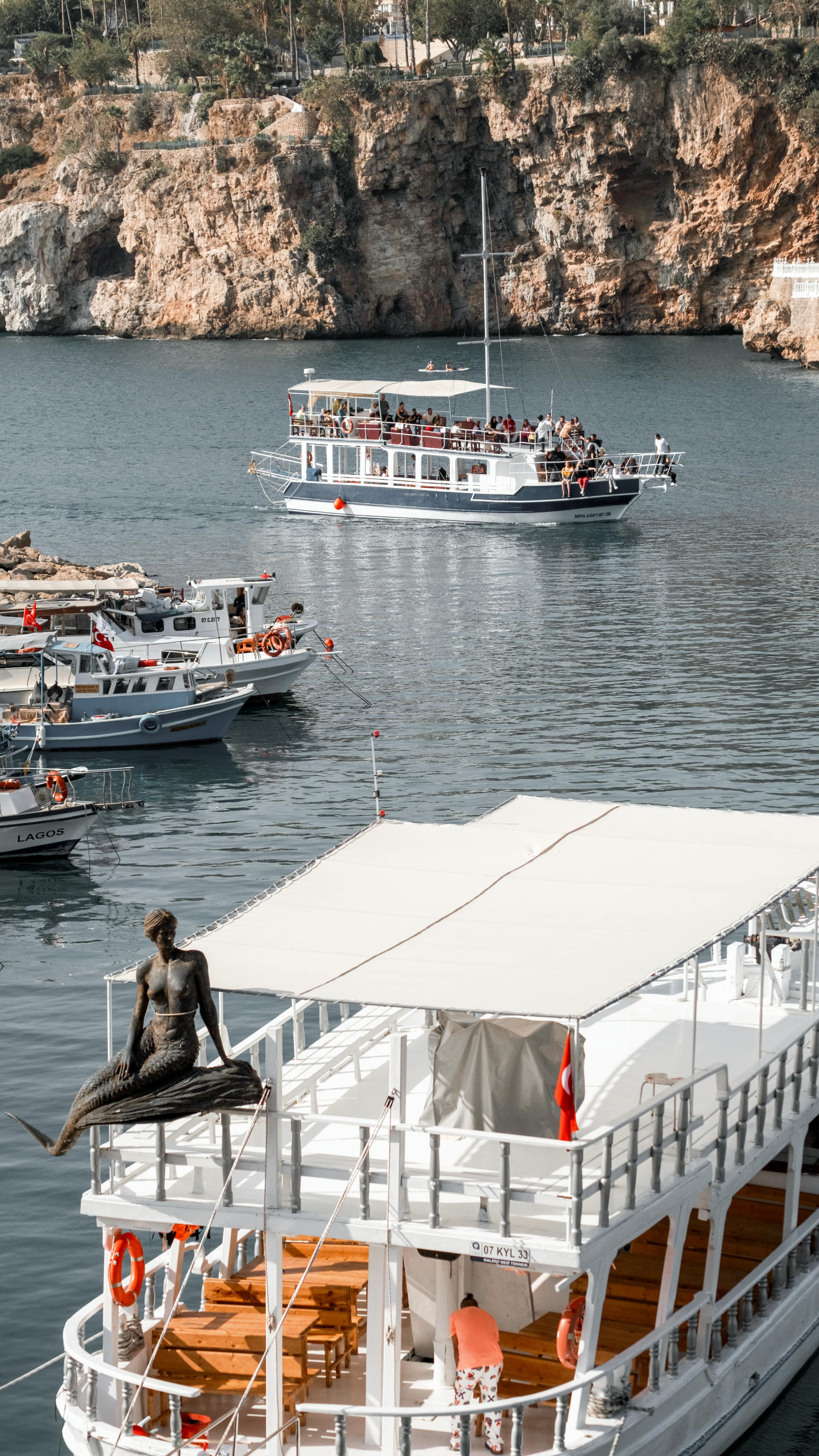 Experience the beautiful coastal view of Antalya's harbor with boats and cliffs, ideal for travel enthusiasts.