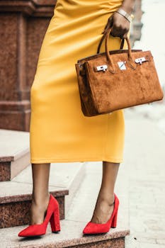 特写一位身穿黄色裙子、脚踩红色高跟鞋、手拿棕色手提包的时尚女性，她正站在楼梯上