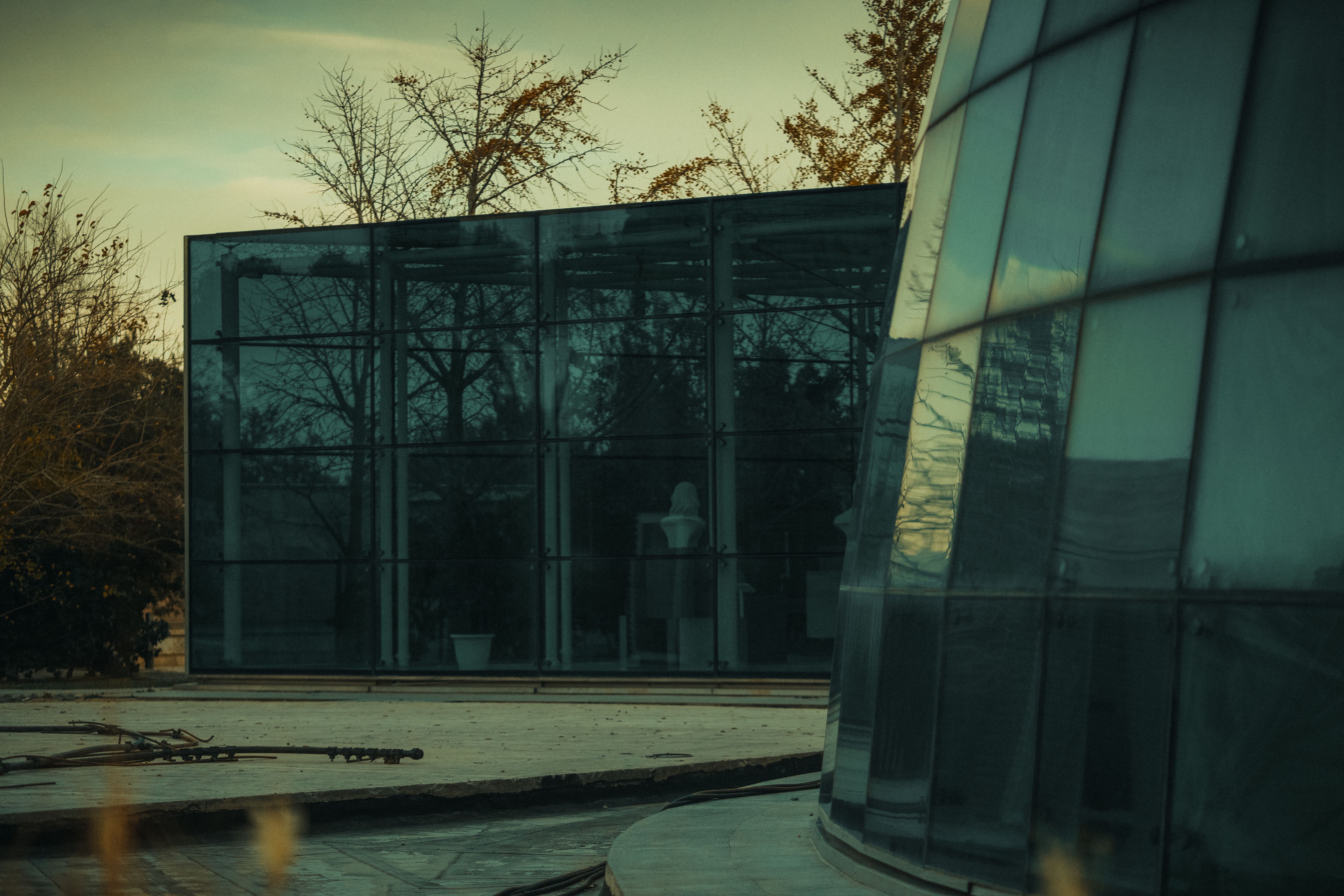 A high-angle shot of a minimalist luxury glass structure reflecting a futuristic city skyline at dawn.