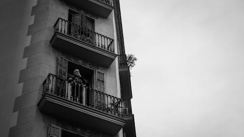 A Man Standing on a Balcony of an Apartment Building in City 