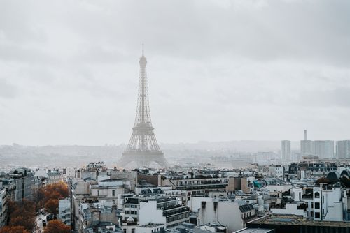 Free Panoramic view of the Eiffel Tower amidst the Parisian rooftops on a foggy day. Stock Photo
