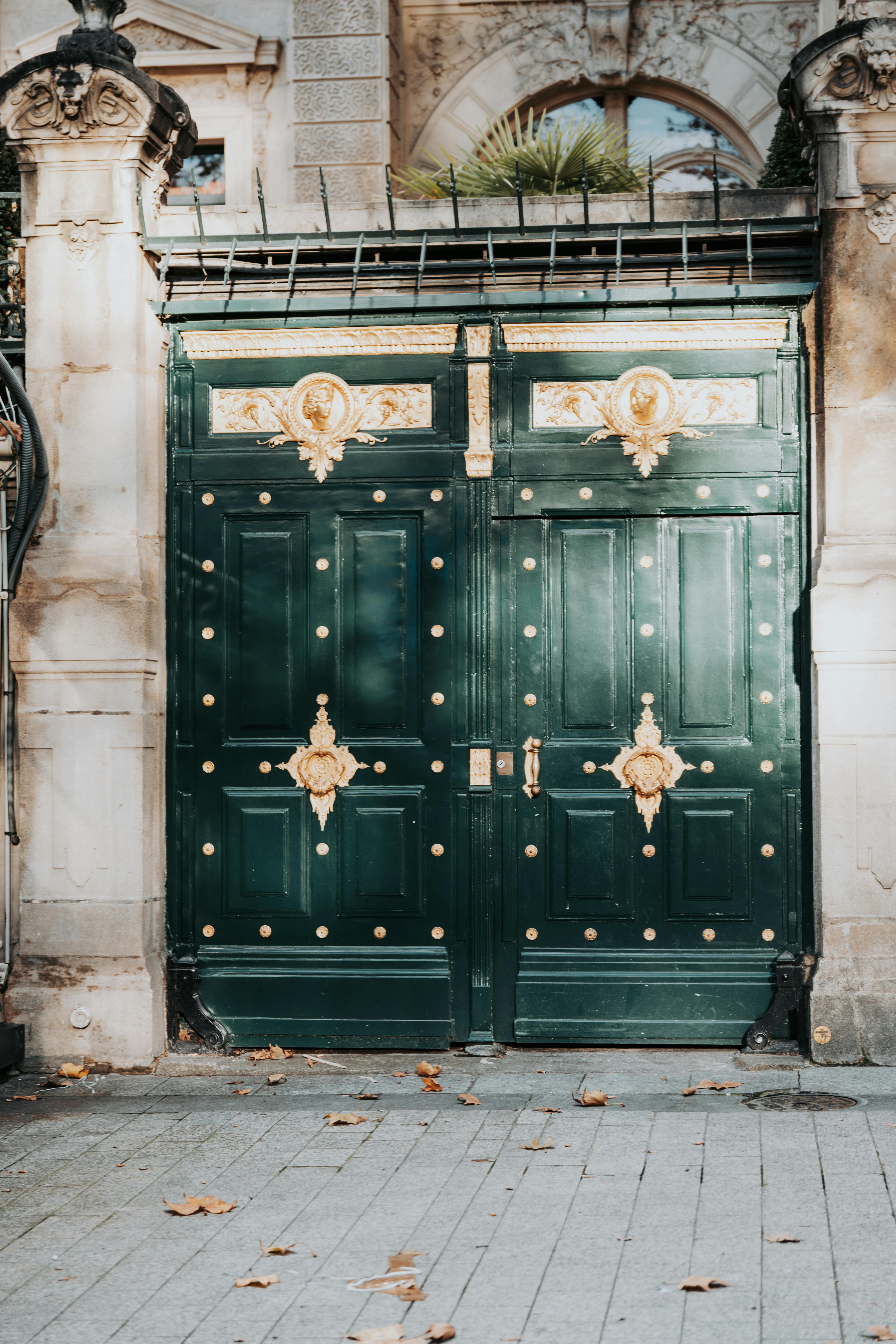 Elegant green gate with golden details in historic Parisian architecture.