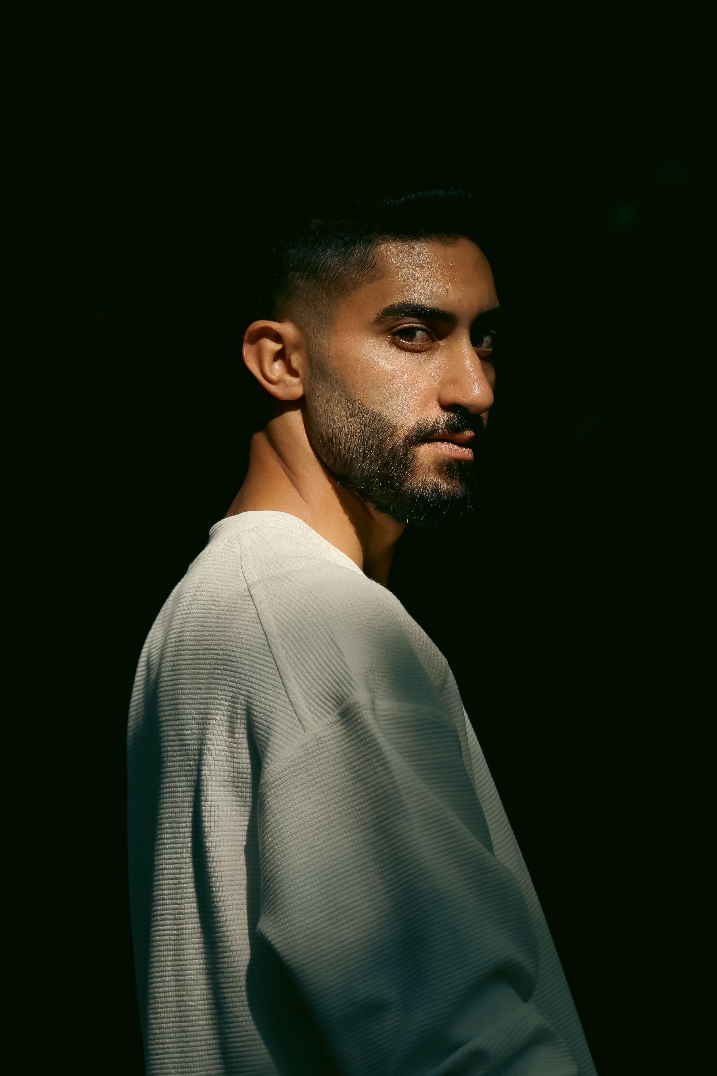 Elegant portrait of a man in white attire with moody lighting. Perfect for editorial and creative use.