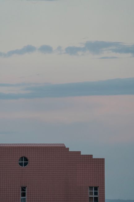 A modern building facade with windows against a pastel sky at dusk, ideal for architectural themes.