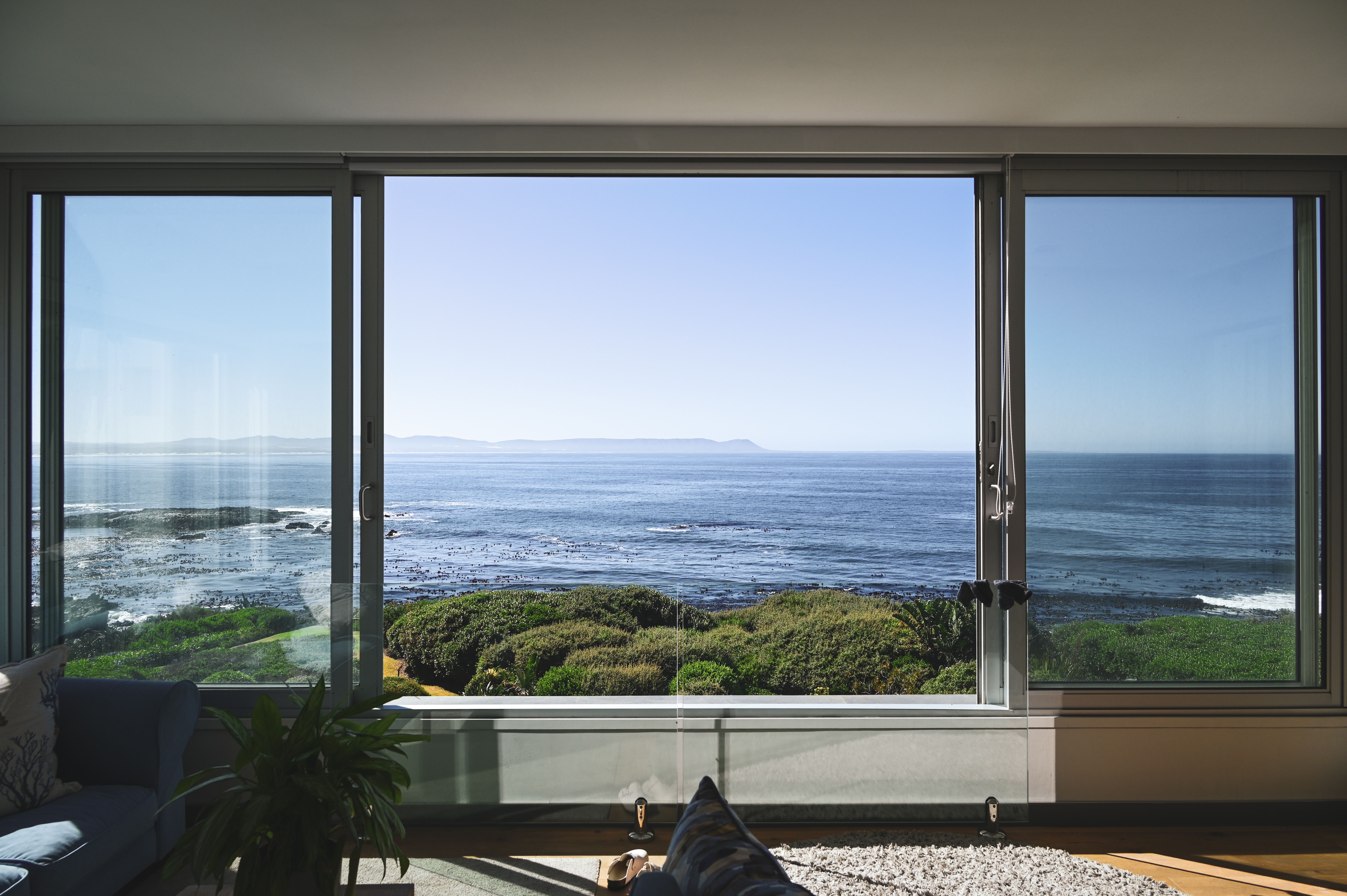 Experience serenity with an ocean view from a sunlit living room in South Africa's coastline.