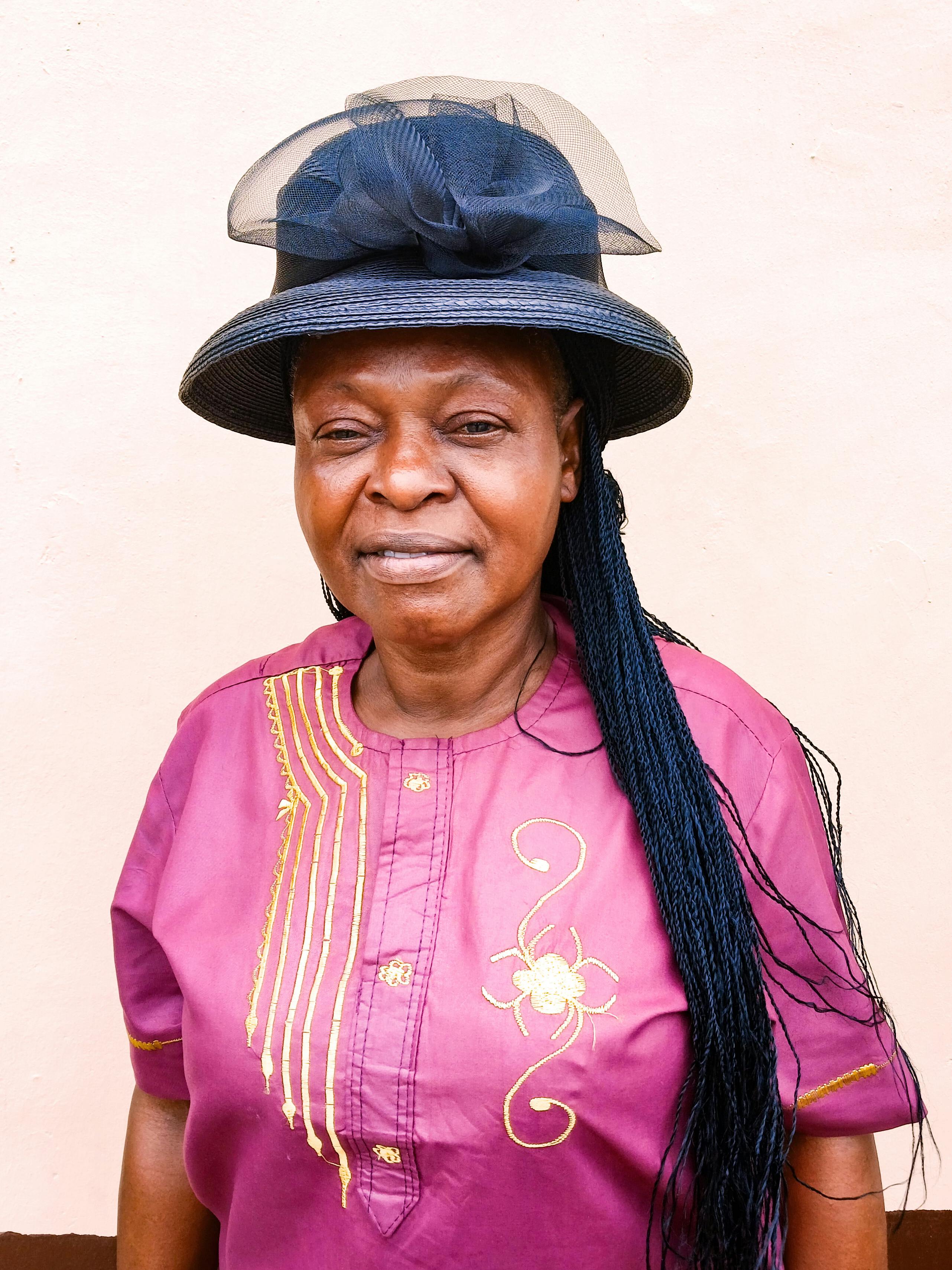 Elderly woman in traditional Nigerian attire with a hat, showcasing cultural heritage.