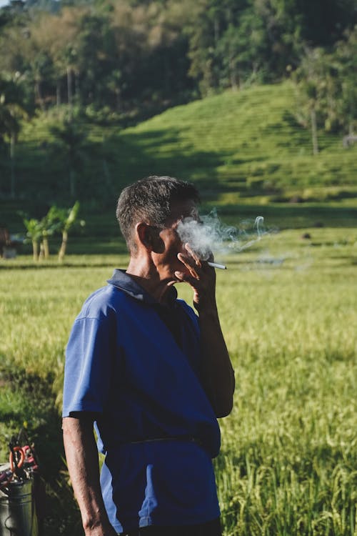 Elderly Man Smoking Cigarette on Green Field