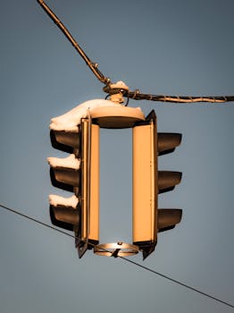 Close-up of a snow-covered traffic light against a clear winter sky in Vienna, Austria.