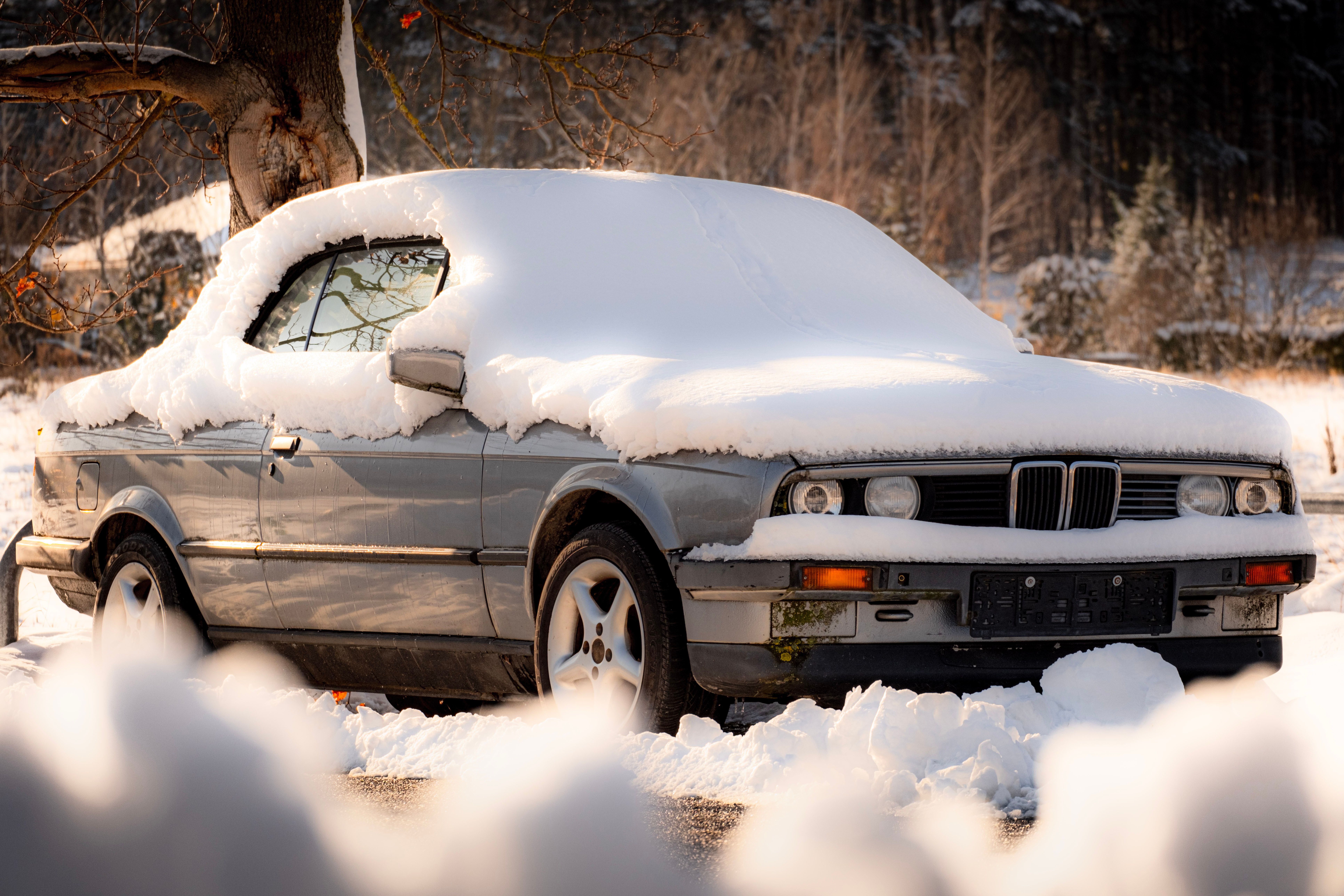 Snow-covered vintage car parked during winter in Vienna.