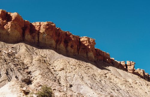 Free A majestic rock formation basking in sunlight with a vibrant blue sky overhead. Stock Photo