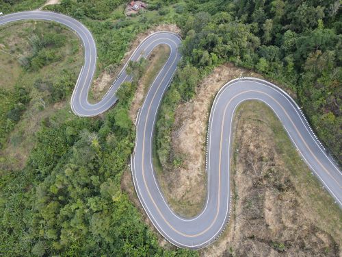 Free Aerial view of a winding road through lush green countryside in Bo Kluea, Thailand. Stock Photo