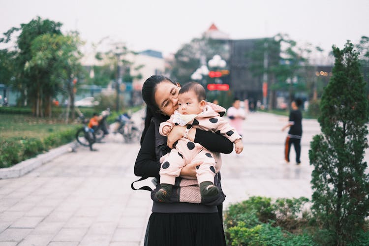 Brunette Mother Standing With Daughter In Park