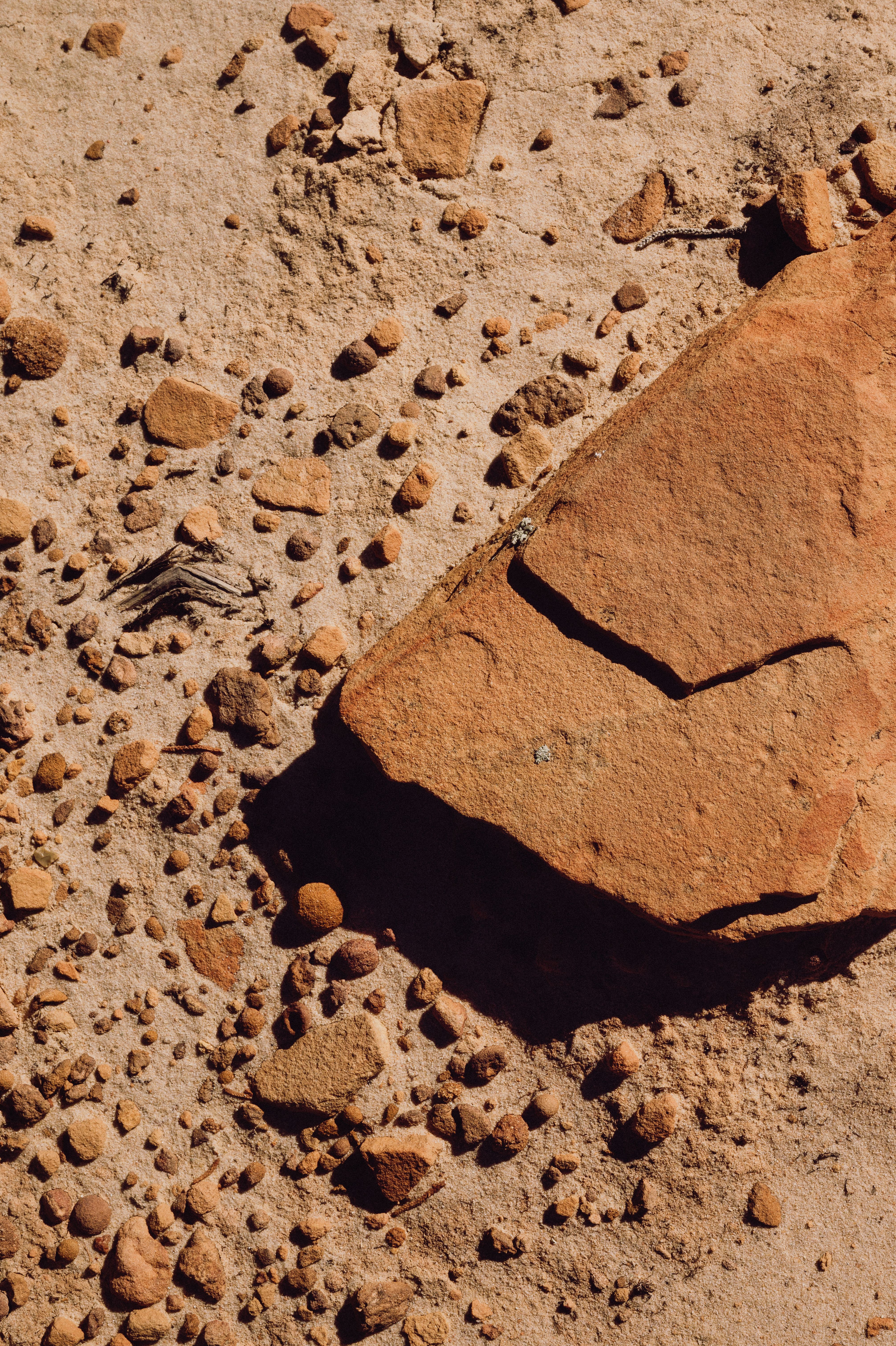Close-up of desert sandstone with scattered rocks showing natural erosion patterns.