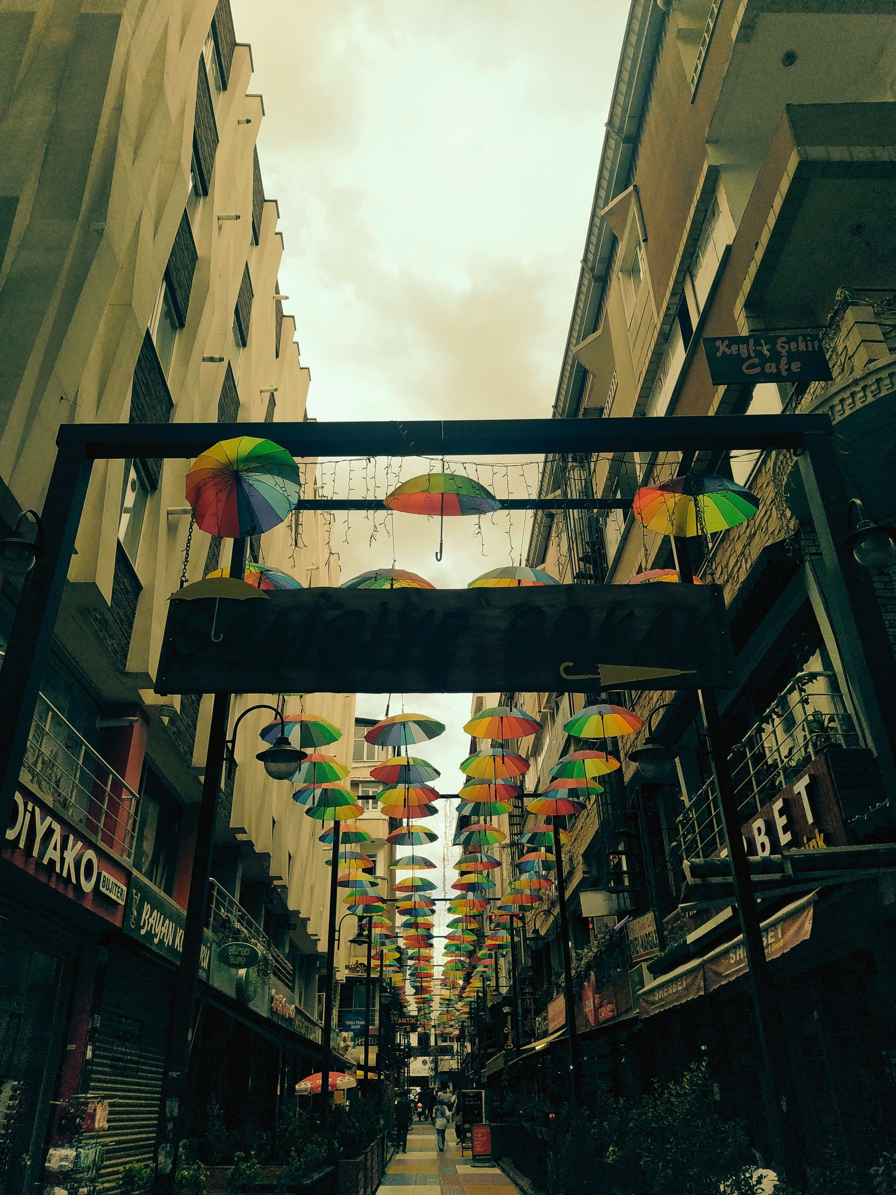 Vibrant umbrellas hang above a narrow city alley, adding colorful decoration to the urban street view.