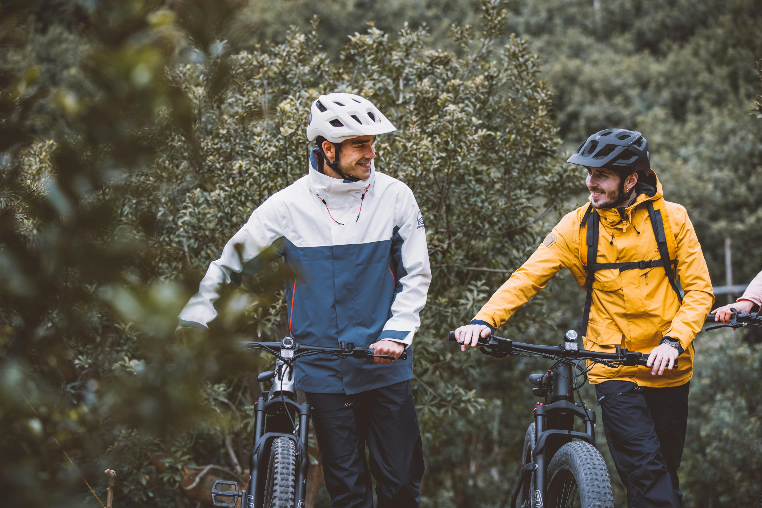 Two men mountain biking in a forest, enjoying the outdoors and having a conversation.