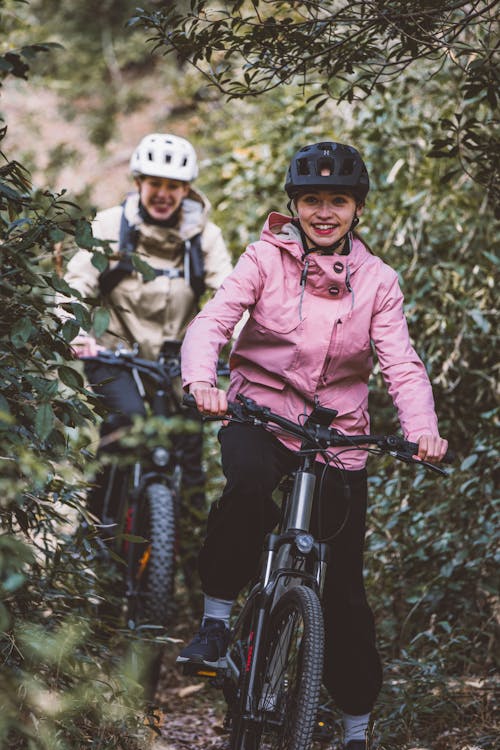 Smiling Women on Bicycles on Footpath in Forest