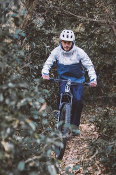 A man cycling through a dense forest trail, showcasing determination and adventure.