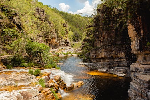 一条风景如画的河流，流经被郁郁葱葱的绿植和蓝天环绕的岩石峡谷