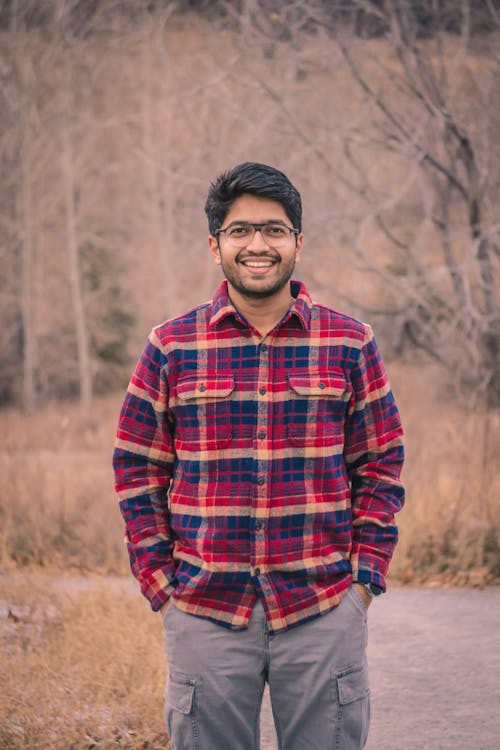Young Man in a Red Plaid Shirt Standing with his Hands in Pockets 