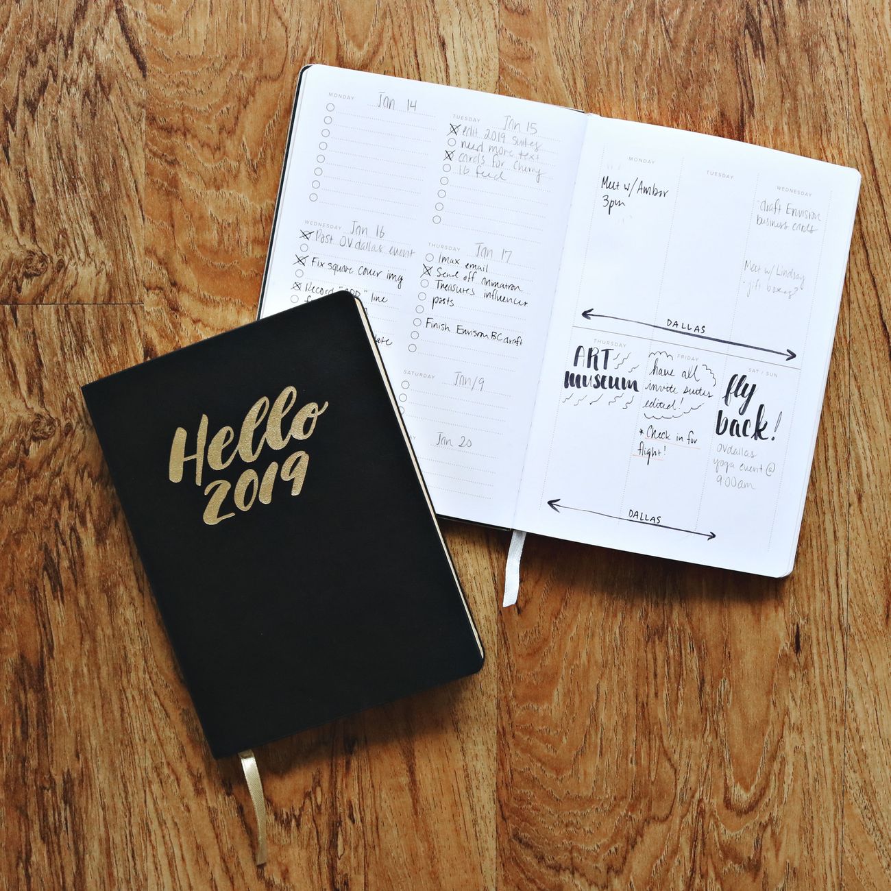 Two 2019 journals open on a wooden floor, showcasing planning and organization.