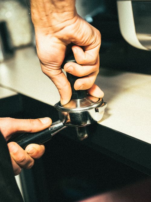 Free Close-up of a barista using a coffee tamper in a Brașov café. Stock Photo