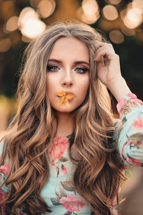 Woman With Orange Petaled Flower on Her Lips