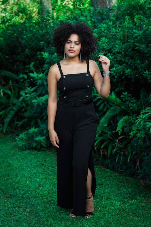 бесплатная Женщина в черном платье стоит рядом с растениями Стоковое фото
