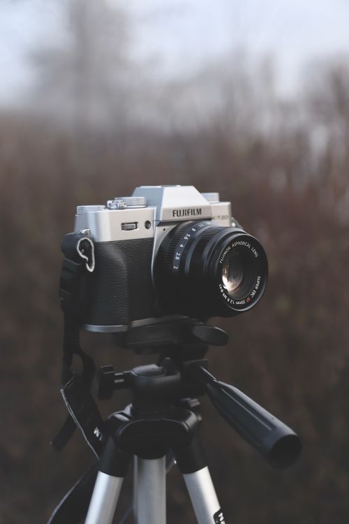 Free Close-up of a vintage camera mounted on a tripod in an outdoor environment. Stock Photo