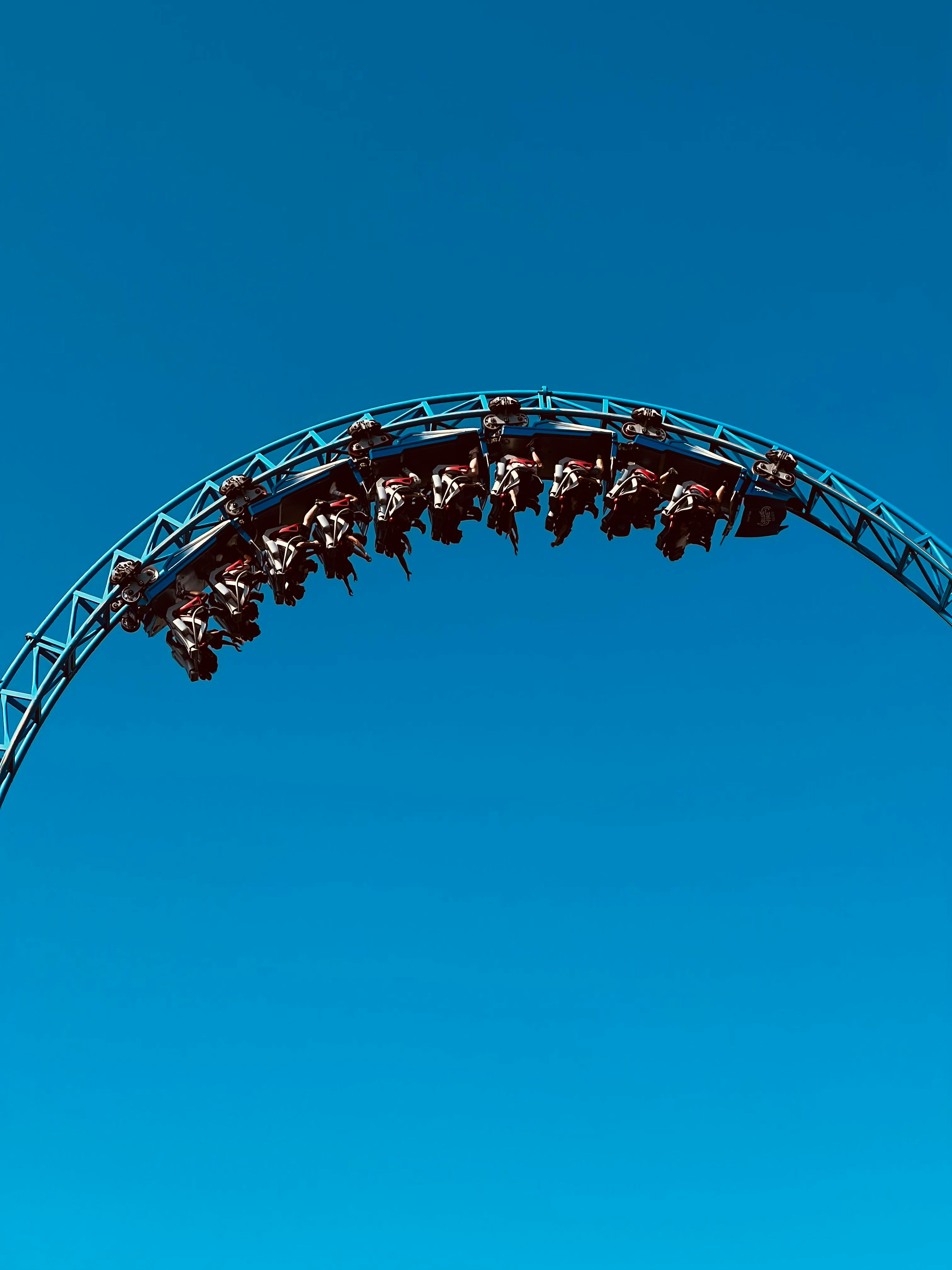 Experience the exhilaration of a roller coaster looping against a stunning blue sky.