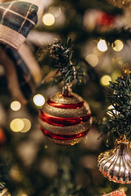 Fotomural Primer plano de un adorno rojo y dorado brillante en un árbol de Navidad decorado.