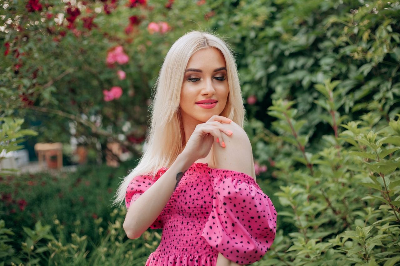 charming portrait of a blonde woman in a pink polka dot dress standing