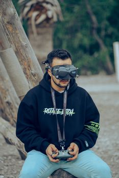 Young man wearing VR goggles and holding a controller, enjoying virtual reality outdoors.