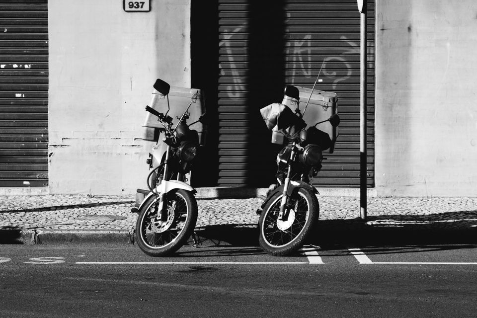 Two motorbikes parked on a city street in black and white — photo by João Saplak on Pexels