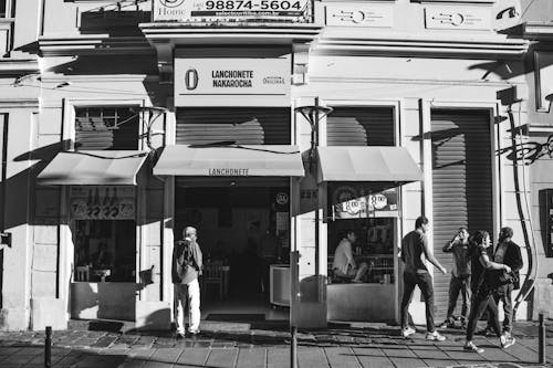 Exterior of a Building with a Bar and People Walking on the Pavement 