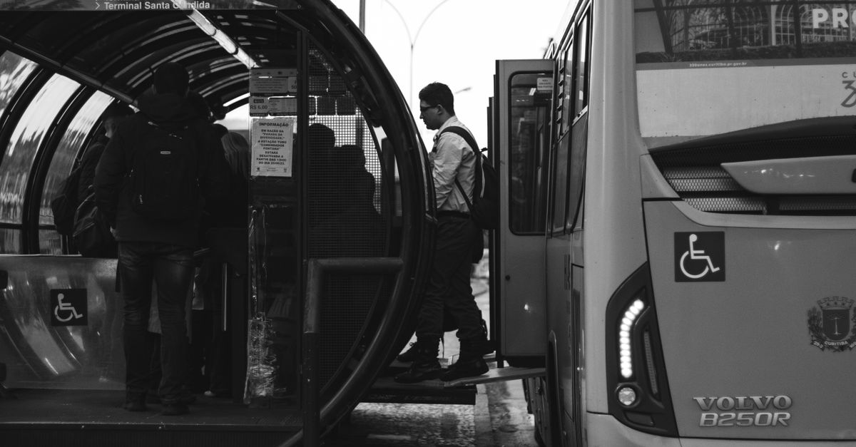 Black and white photo of people boarding a city bus at a modern bus station.