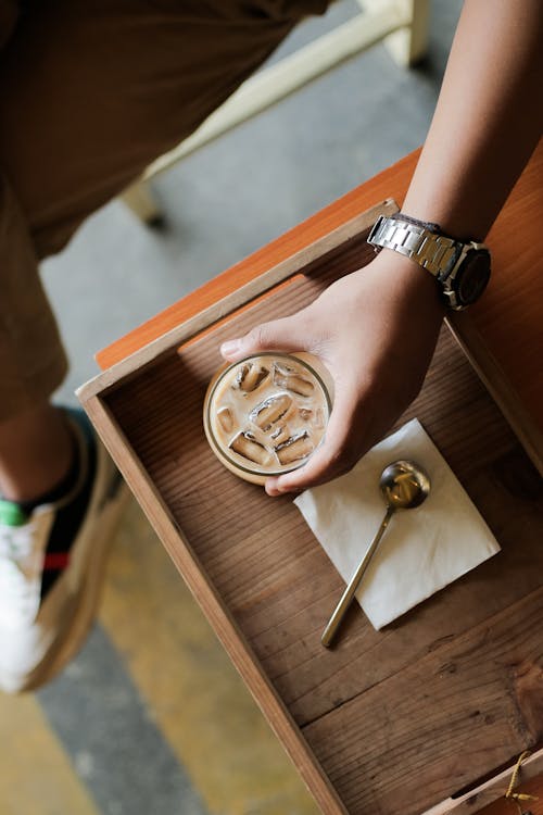 Top View of a Person Grabbing a Glass with Iced Coffee