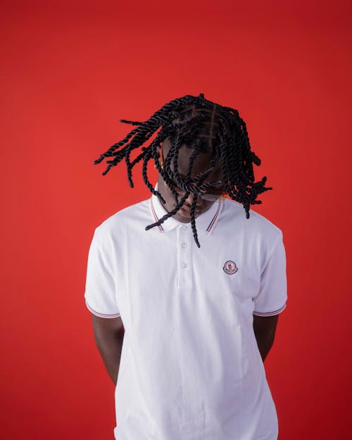 Man with Dreadlocks Wearing a White T-shirt Posing on Red Background 