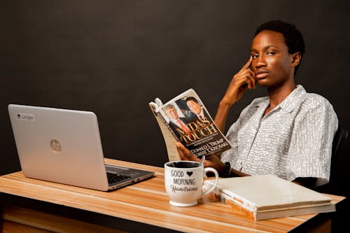 Young Man Sitting at the Desk and Reading a Book 